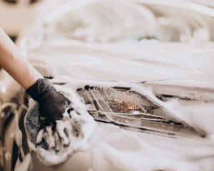 Main qui nettoie une voiture avec de la mousse en Valais Garage du Rocher