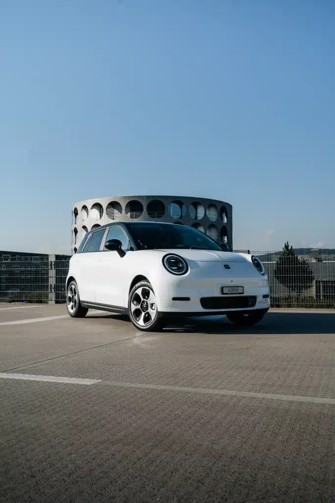 Citadine JAC E30X blanc roulant sur une route sur fond de ciel bleu