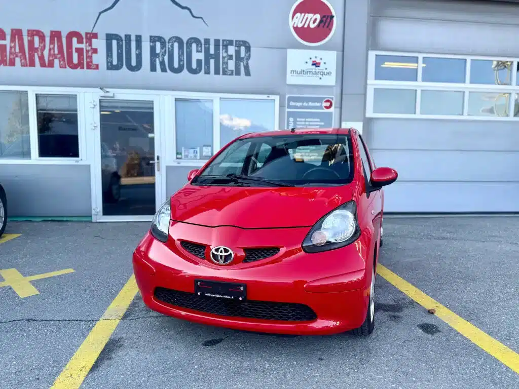 Toyota Aygo rouge exposée de face devant le Garage du Rocher