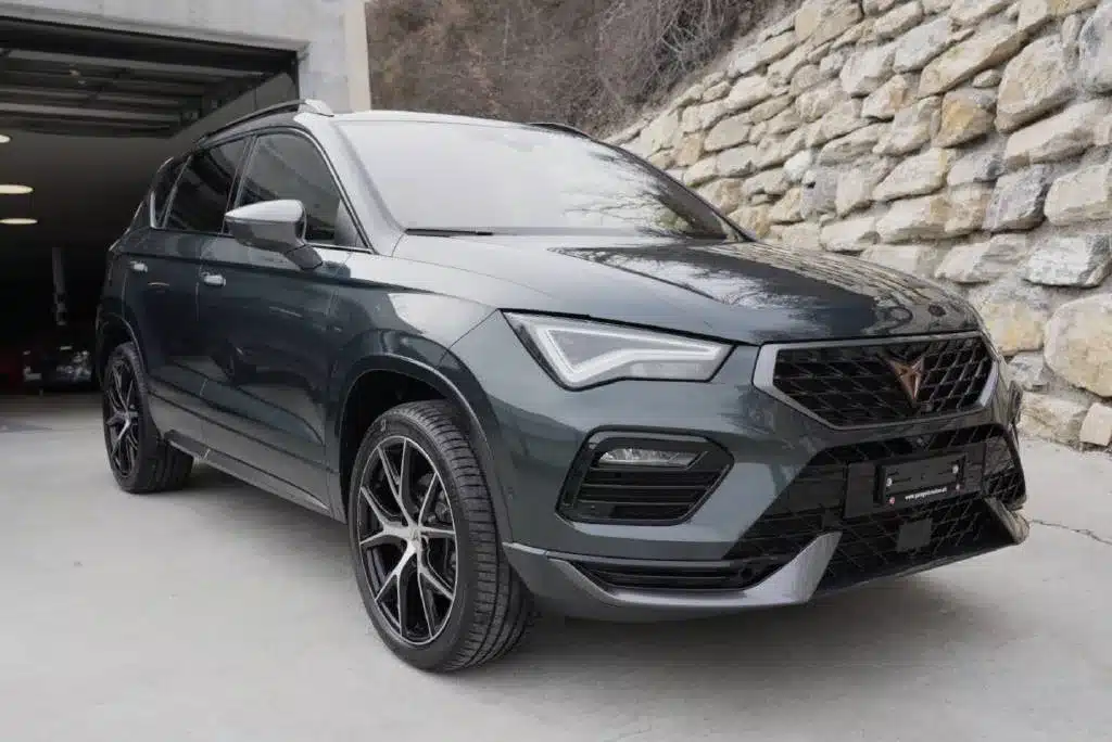 Cupra Ateca 4X4 grise d'occasion stationnée devant un mur de pierres au Garage du Rocher