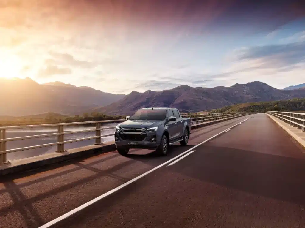 ISUZU roulant sur route avec des montagnes et un coucher de soleil en arrière plan