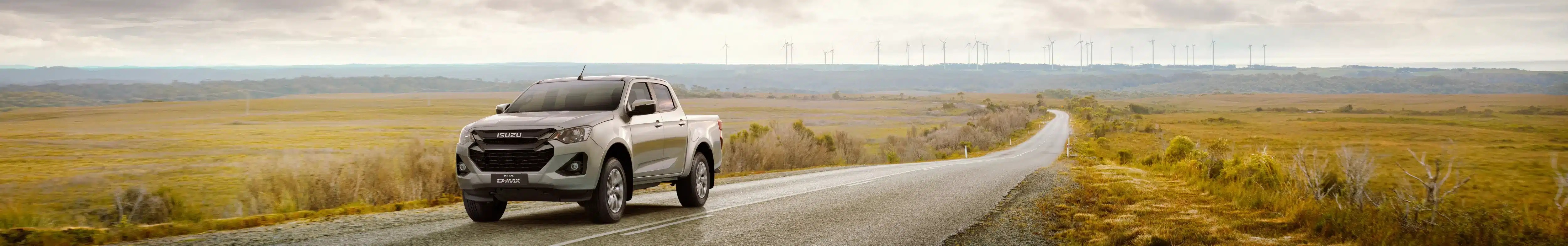 ISUZU D-MAX roulant sur une belle route goudronnée avec campagne et ciel gris en arrière plan