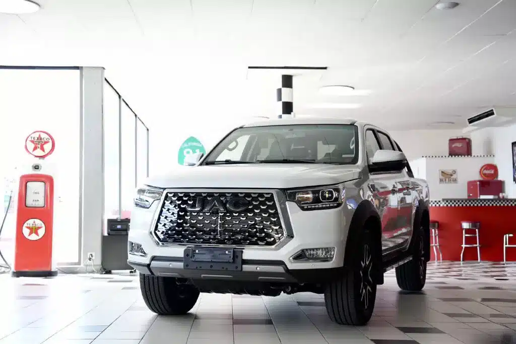 JAC T8 pro diesel blanc exposé dans un showroom avec décor style américain avec une colonne à essence ancienne