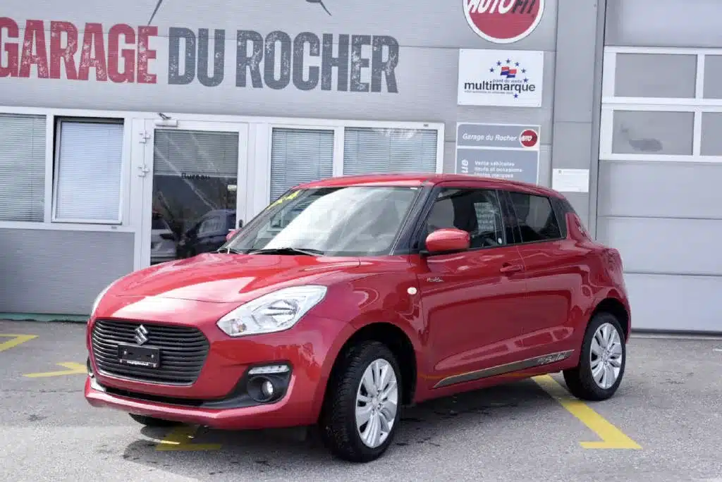 Suzuki Swift 4X4 hybrid d'occasion parqué en expo devant le garage du Rocher en Valais