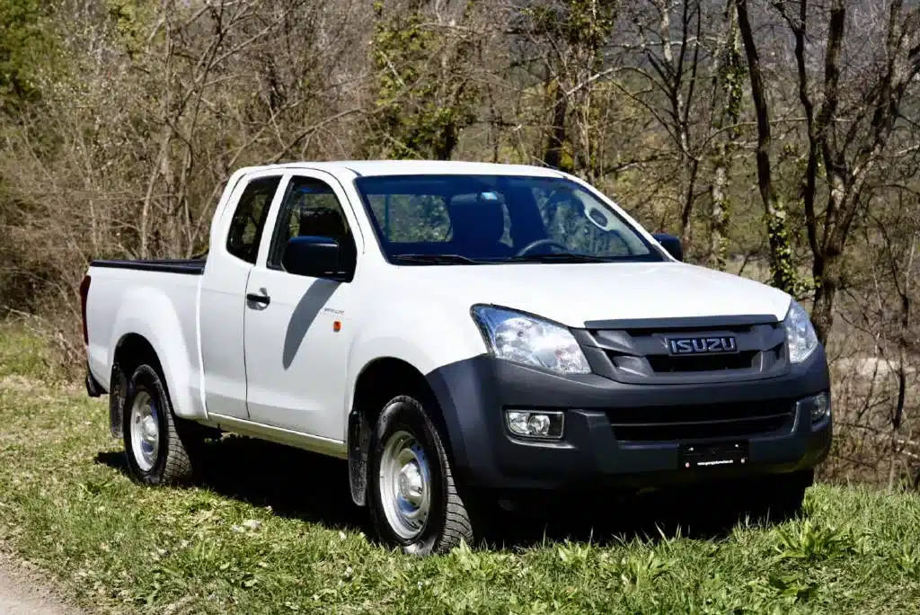 ISUZU D-Max Space d'occasion pick-up blanc exposé sur de l'herbe pour le Garage du Rocher en valais
